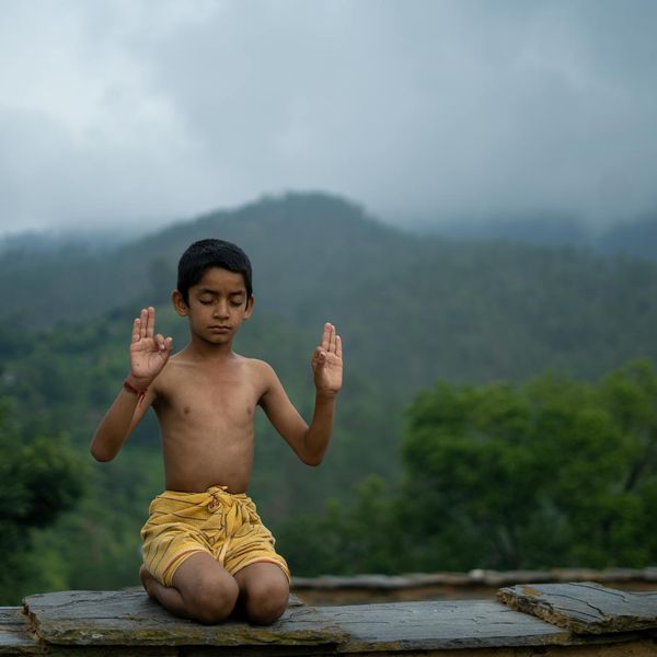 A calm person meditating outdoors with a serene natural landscape in the background.